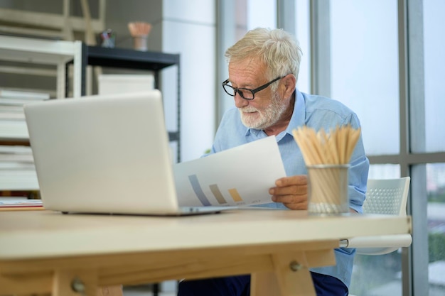 Ein kaukasischer älterer Geschäftsmann, der in einem modernen Büro arbeitet