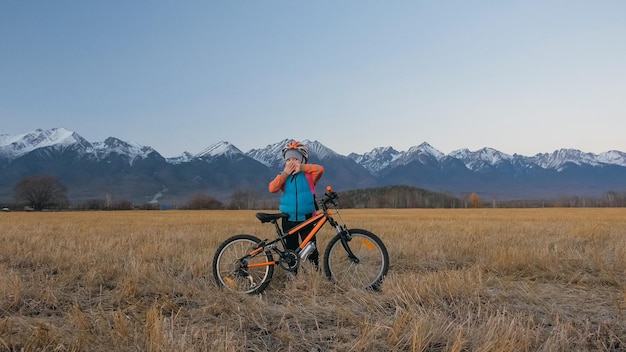 Ein kaukasischer Kinder gehen mit dem Fahrrad im Weizenfeld Kleines Mädchen zu Fuß schwarz orange Zyklus
