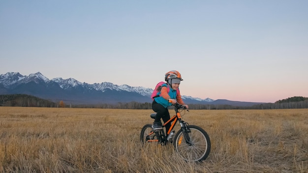 Ein kaukasischer Kinder gehen mit dem Fahrrad im Weizenfeld Kleines Mädchen zu Fuß schwarz orange Zyklus