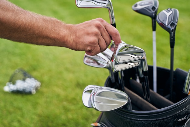 ein kaukasischer Mann, der in einer Ledertasche nach einem Golfschläger greift