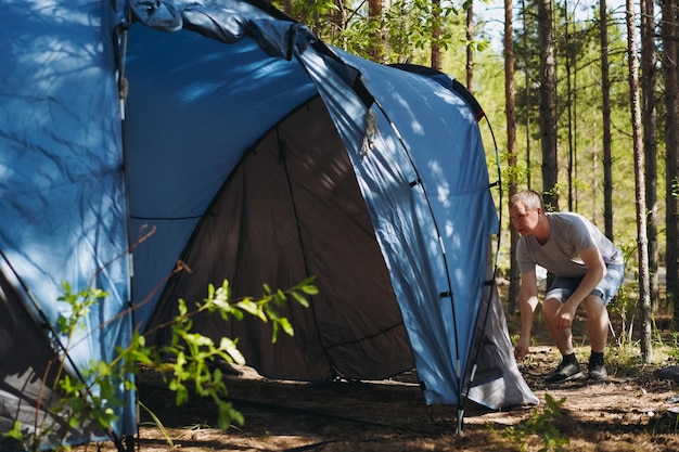 ein kaukasischer Mann mit Hut, der ein Zelt aufstellt, Familiencamping-Konzept