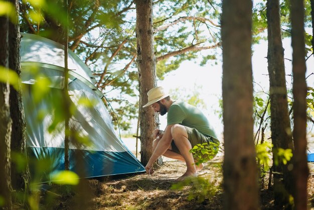 ein kaukasischer Mann mit Hut, der ein Zelt aufstellt, Familiencamping-Konzept