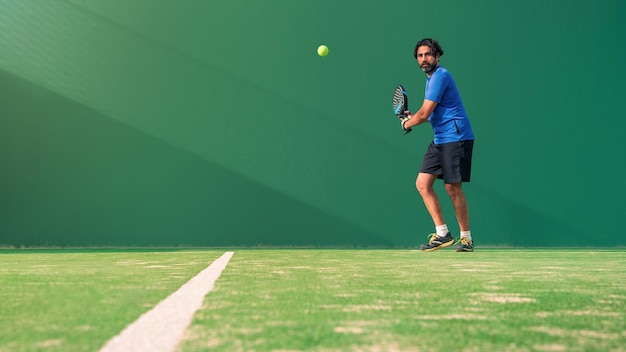 Ein kaukasischer Padelspieler springt zum Ball und sucht nach Posts und Plakaten