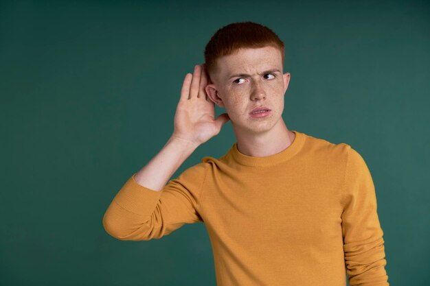 Ein kaukasischer Teenager, der auf grünem Hintergrund lauscht
