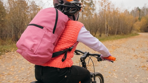 Ein kaukasisches Kind reitet Fahrradstraße im Herbstpark Kleines Mädchen, das im Wald einen schwarzen orangefarbenen Zyklus reitet