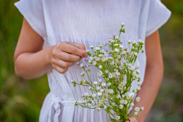 Ein kaukasisches Mädchen der Hippie, das einen Blumenstrauß von Wildblumen in ihren Händen hält.