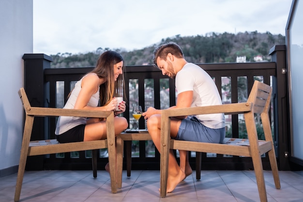 Ein kaukasisches Paar, das auf der Hotelterrasse im Pyjama frühstückt. Morgens mit Orangensaft rösten, Lebensstil eines verliebten Paares