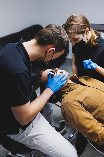 Ein Kieferorthopäde behandelt die Zähne seines Patienten in einem modernen, hellen Büro Kieferorthopädische Behandlung von Zähnen