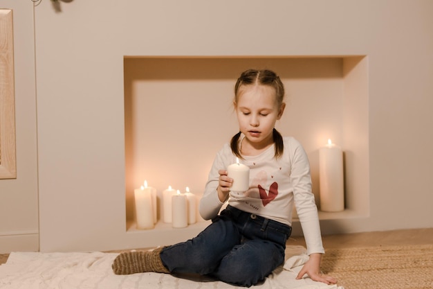Ein Kind am Kamin hält eine brennende Kerze