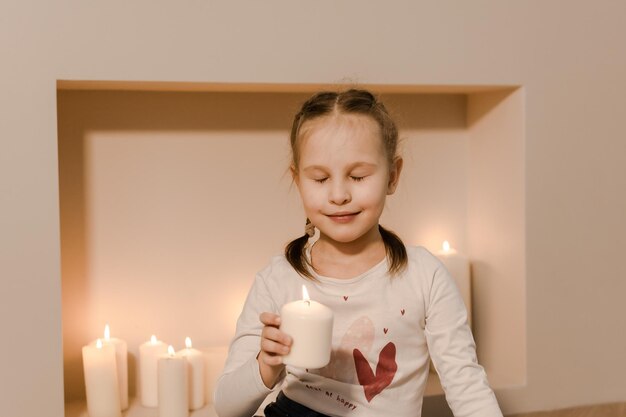 Foto ein kind am kamin hält eine brennende kerze