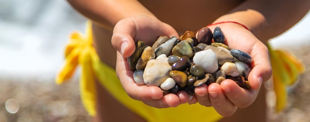 Ein Kind am Strand hält Meeressteine in den Händen. Selektiver Fokus.