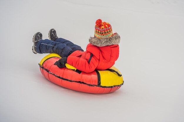 Foto ein kind amüsiert sich auf einer schnee-röhre, ein junge fährt auf einer schlauchröhre, winter-spaß für kinder.