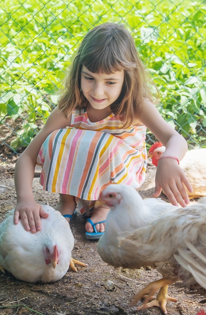 Ein Kind auf einem Bauernhof mit einem Huhn.