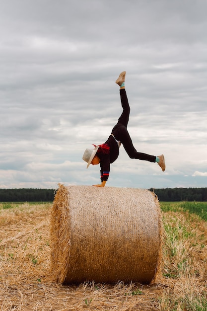 Ein Kind auf einem Heuhaufen macht einen Handstand unbeschwerte Kindheit auf dem Land Sommerstimmung Leben auf der Ferne