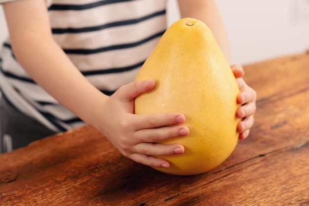 Ein Kind hält einen leuchtend gelben Pomelo, der Frische und die gesundheitlichen Vorteile von gesunden Früchten ausstrahlt