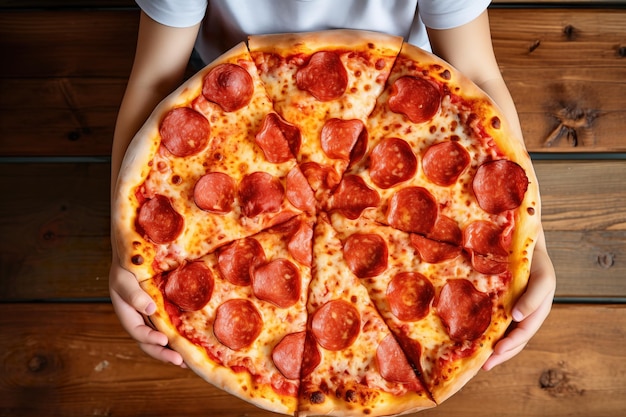 Foto ein kind hält freudig eine große pepperoni-pizza in den händen, gesehen von oben