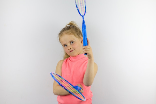 Ein Kind hält zwei blaue Tennisschläger. Sporthaltung. Unterhaltung