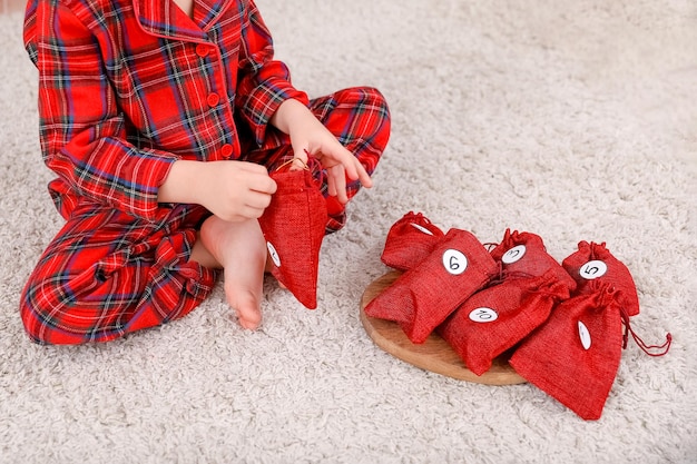 Ein kind im pyjama öffnet die adventskalendertüte mit überraschung