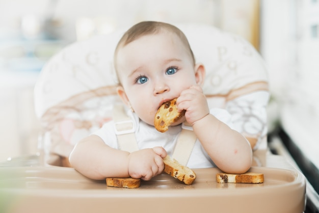 Foto ein kind in einem hochstuhl isst einen cracker mit rosinen