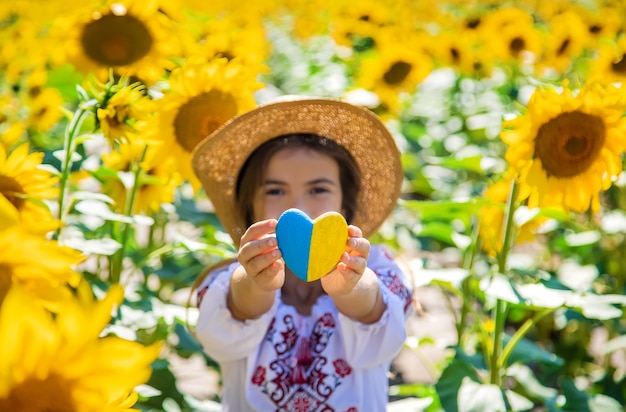 Ein Kind in einem Sonnenblumenfeld in einem bestickten Hemd. Ukraine-Unabhängigkeitstag-Konzept. Selektiver Fokus.