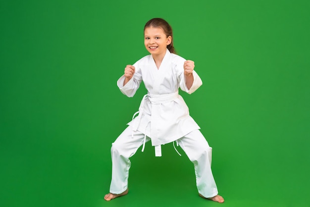 Ein Kind in einem weißen Kimono Kampfkunst aus einer frühen Kinderdisziplin ein Karate-Mädchen auf grünem Hintergrund Wettbewerbe in der Kampfkunst