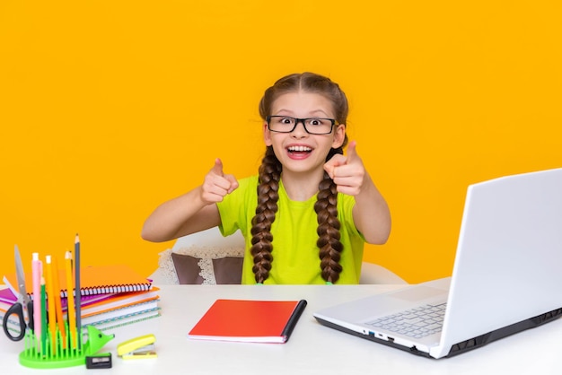 Ein Kind mit Brille sitzt an einem Schreibtisch ein glückliches kleines Mädchen sitzt an ihrem Laptop Kinderschule Fernunterricht online