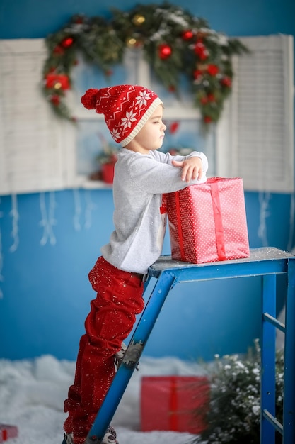 Foto ein kind mit einem roten hut allein hält am neujahrstag eine schachtel rot.