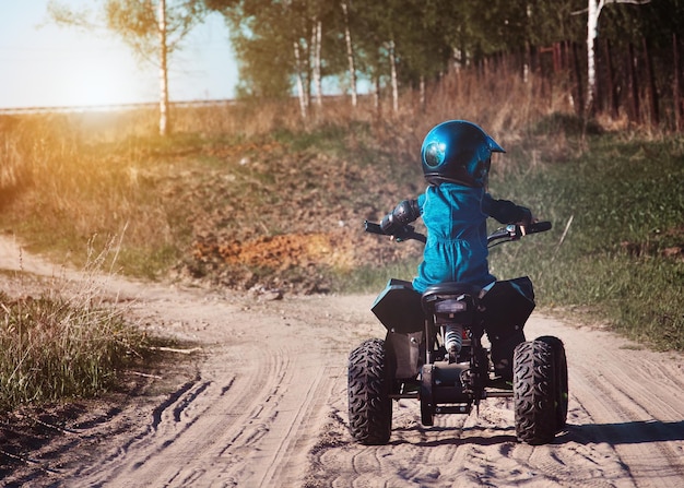 Foto ein kind mit helm fährt auf einem kinder-quad