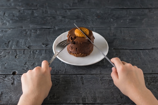 Ein Kind mit Messer und Gabel in den Händen beginnt, frisch zubereitetes Dessert zu essen