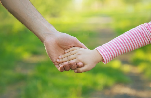 Ein Kind mit seinem Vater geht an der Hand. Selektiver Fokus