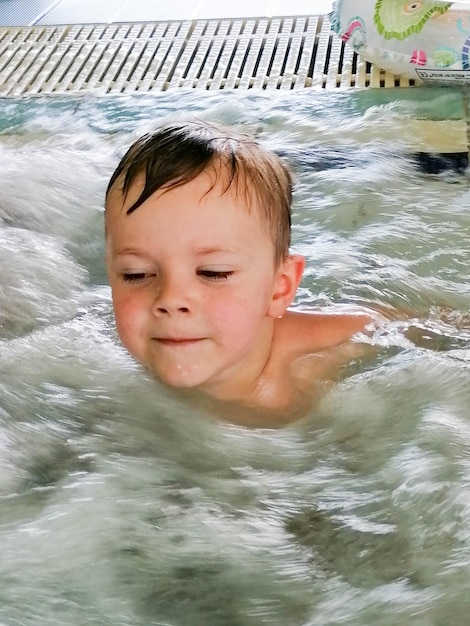 Ein Kind schaut sich die Schaumbellen im Pool an