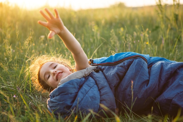 Foto ein kind schläft in einem schlafsack auf dem rasen bei einem campingausflug umweltfreundliche erholung im freien gesunder lebensstil sommerzeit süßer und friedlicher schlaf mückenstiche abweisend