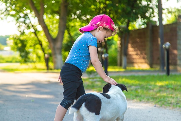 Ein Kind spielt mit einem kleinen Hund im Park. Selektiver Fokus