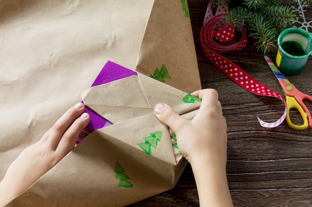 Ein Kind verpackt Papier mit Weihnachtsgeschenkbox und einem Schneemann mit Süßigkeiten Kinderkunst