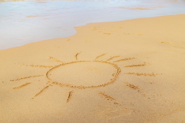 Ein Kind zeichnet eine Sonne am Strand.