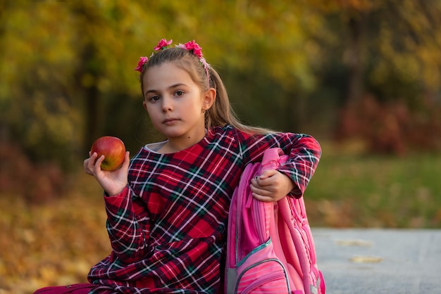 Ein Kindermädchen, das ein gesundes Frühstück im Herbstpark beim Mittagessen in der Schule isst.