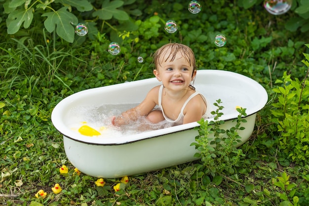 Ein Kindermädchen in einem Retro-Bad badet in der Natur und lacht.