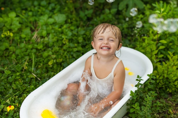 Ein Kindermädchen in einem Retro-Bad badet in der Natur und lacht.