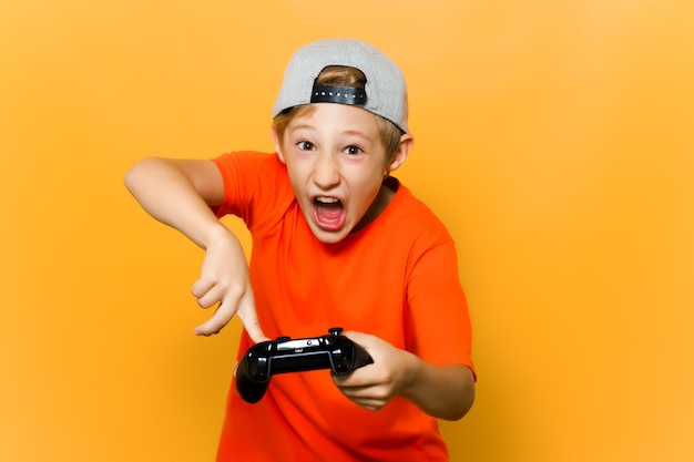 Ein Kinderspieler hält ein Gamepad in den Händen und zeigt Emotionen durch Drücken der Tasten