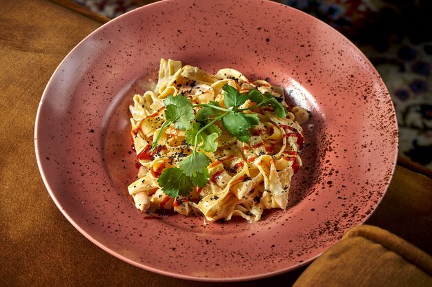 Ein klassisches italienisches Gericht - Fetuccini-Nudeln mit Garnelen, Käse und weißer Sauce, serviert auf einem rosa Teller. Restaurant Essen. Sicht von oben