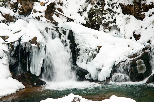 ein kleiner aktiver Wasserfall sauberer Gebirgsbach verschneite Winterlandschaft Tierwelt Hintergrund