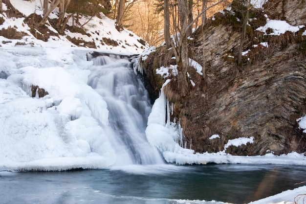 ein kleiner aktiver Wasserfall sauberer Gebirgsbach verschneite Winterlandschaft Tierwelt Hintergrund