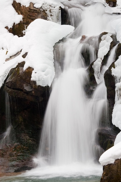 ein kleiner aktiver Wasserfall sauberer Gebirgsbach verschneite Winterlandschaft Tierwelt Hintergrund