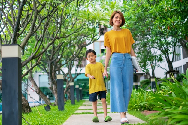 Ein kleiner asiatischer Junge mit seiner Mutter geht in Garten