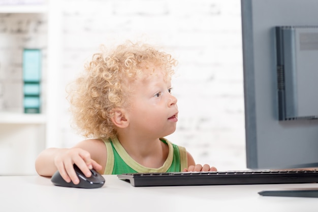 Foto ein kleiner blonder junge, der mit computer spielt