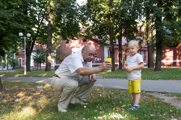 Ein kleiner Enkel in gelben Shorts und ein glatzköpfiger Großvater aßen nachlässig Popcorn und verstreuten es aus einem gelben Glas Unordnung auf dem Boden