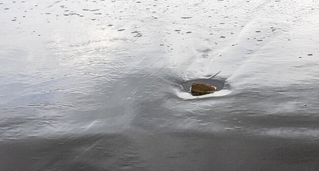 Ein kleiner Felsen auf einem Sandland am Meeresstrand