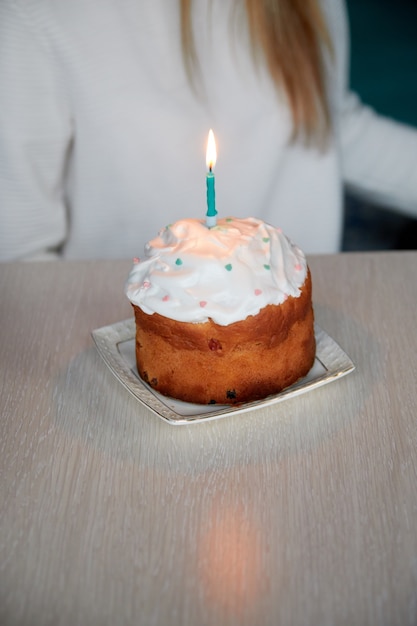 Ein kleiner festlicher Kuchen mit einer brennenden Kerze auf dem Tisch zum Geburtstag