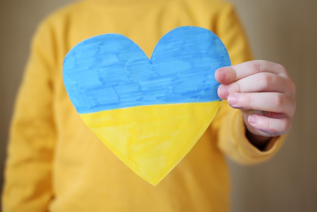 Ein kleiner Flüchtlingsjunge aus der Ukraine mit einer Zeichnung der ukrainischen Flagge