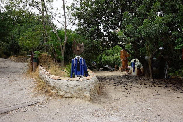 Ein kleiner Garten mit der Statue eines Mannes, der ein blaues Hemd und einen Hut trägt.